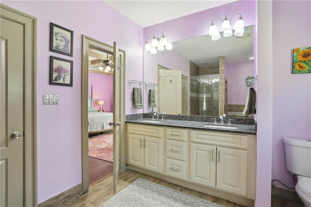 bathroom featuring toilet, a shower with shower door, hardwood / wood-style floors, vanity, and ceiling fan