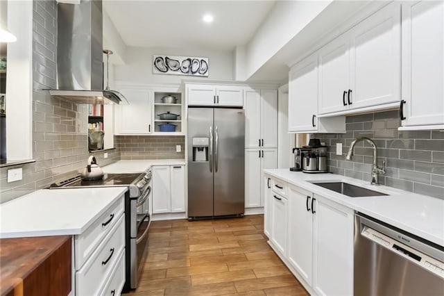 kitchen featuring wall chimney exhaust hood, stainless steel appliances, sink, light hardwood / wood-style flooring, and white cabinets