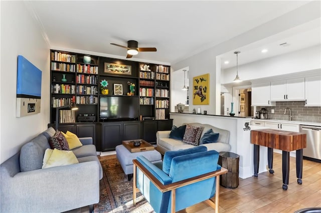 living area with ceiling fan, sink, dark hardwood / wood-style floors, and ornamental molding