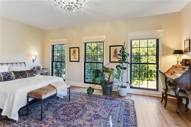 bedroom with multiple windows, hardwood / wood-style floors, and an inviting chandelier