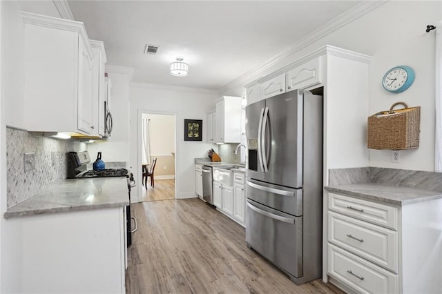 kitchen featuring decorative backsplash, crown molding, light stone countertops, appliances with stainless steel finishes, and white cabinets