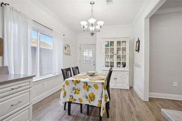 dining space featuring a wealth of natural light, an inviting chandelier, ornamental molding, and light hardwood / wood-style floors