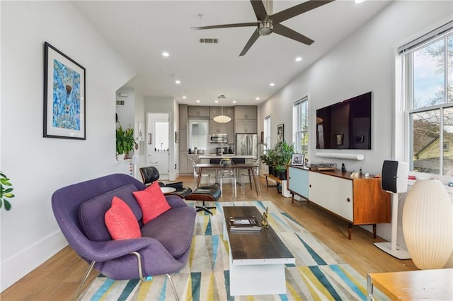 living room with ceiling fan and light wood-type flooring