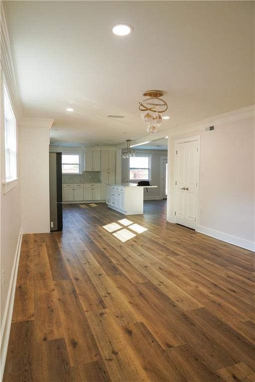 unfurnished living room with crown molding, dark wood-type flooring, and a healthy amount of sunlight