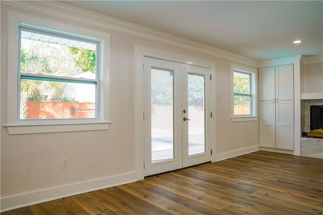 doorway to outside with ornamental molding, dark hardwood / wood-style flooring, plenty of natural light, and a tile fireplace