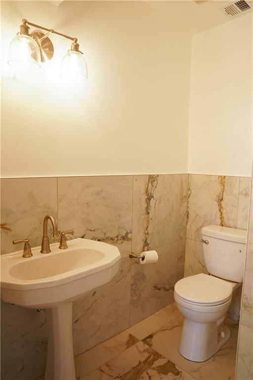 bathroom featuring toilet and tile walls