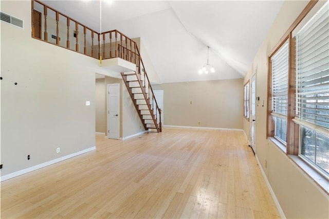 59449 Donya St, Slidell, LA 70460 - unfurnished living room with light wood-style flooring, visible vents, an inviting chandelier, stairs, and high vaulted ceiling