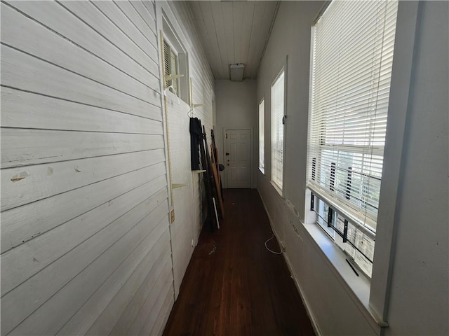 hallway with dark hardwood / wood-style flooring and wood walls