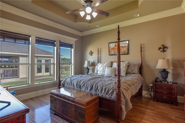 bedroom with hardwood / wood-style floors, crown molding, a tray ceiling, and ceiling fan