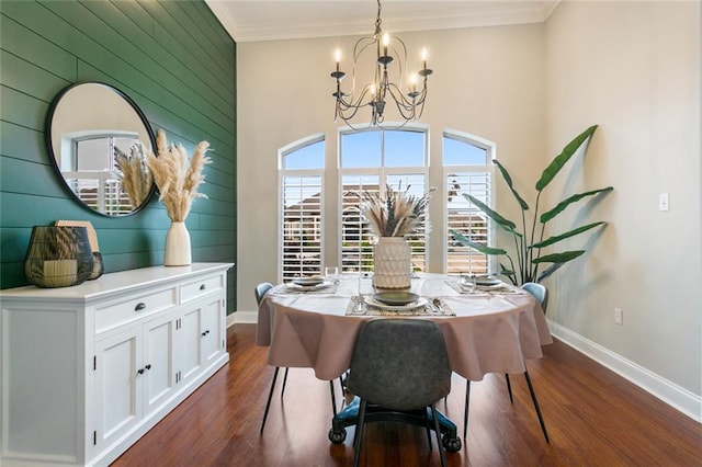 dining room featuring dark wood-type flooring, wooden walls, ornamental molding, and a chandelier