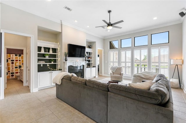 tiled living room featuring crown molding, built in features, and ceiling fan