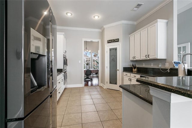 kitchen featuring stainless steel refrigerator with ice dispenser, dark stone countertops, ornamental molding, light tile patterned flooring, and white cabinets