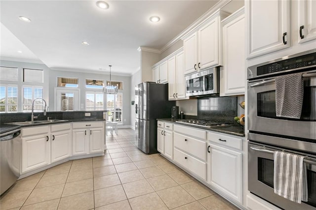 kitchen featuring light tile patterned flooring, sink, white cabinetry, stainless steel appliances, and pendant lighting