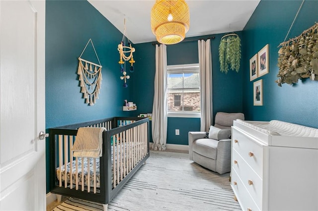 bedroom with light hardwood / wood-style flooring and a nursery area