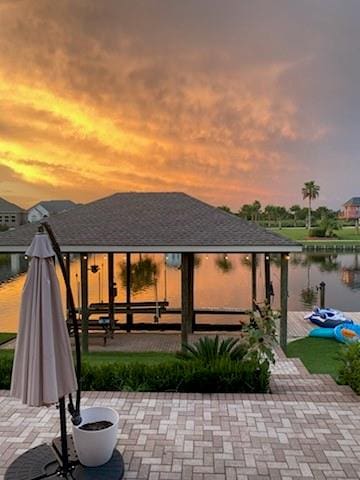 patio terrace at dusk featuring a water view