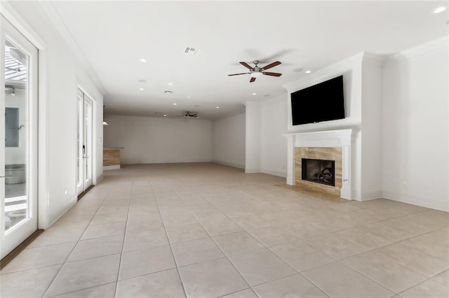 unfurnished living room featuring ornamental molding, ceiling fan, a tile fireplace, and light tile patterned floors