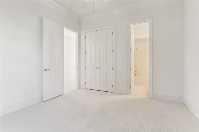 unfurnished bedroom with ceiling fan, crown molding, a closet, ensuite bath, and light colored carpet