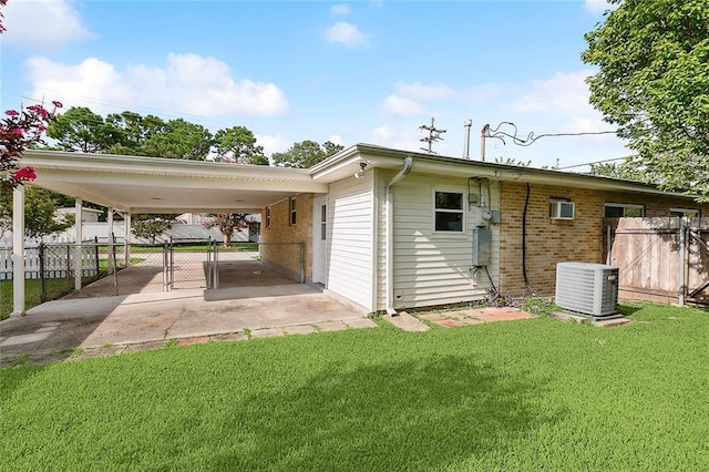 rear view of property with central air condition unit, a lawn, and a carport