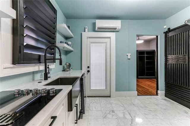 kitchen featuring light wood-type flooring, a wall mounted air conditioner, a barn door, stainless steel dishwasher, and white cabinets