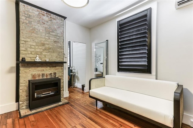 sitting room with wood-type flooring and a wall mounted air conditioner