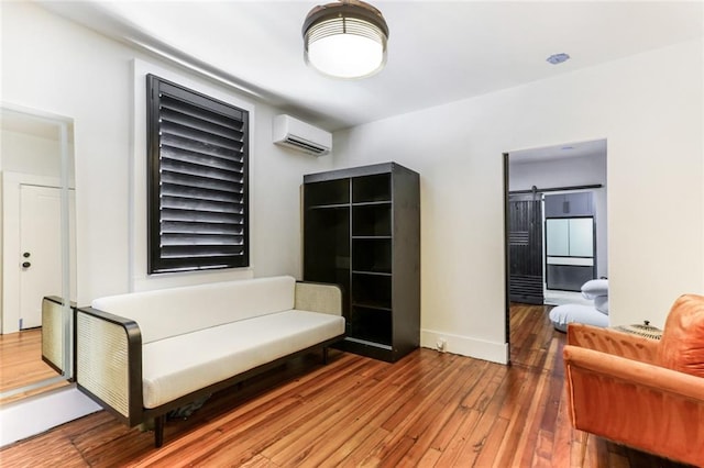 living area with an AC wall unit, wood-type flooring, and a barn door