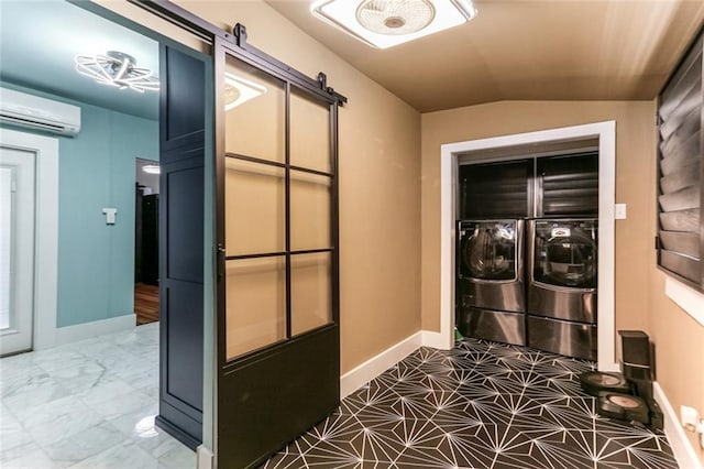 washroom featuring a wall mounted air conditioner, a barn door, and washing machine and dryer