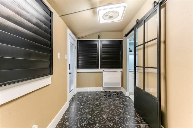 doorway featuring lofted ceiling, a barn door, and dark tile patterned floors