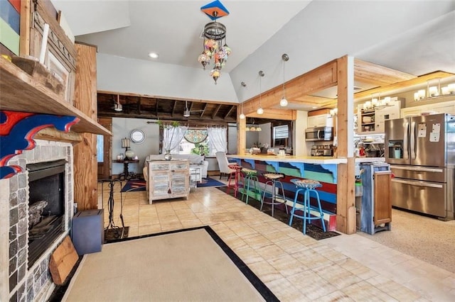 kitchen featuring appliances with stainless steel finishes, a fireplace, kitchen peninsula, pendant lighting, and light colored carpet