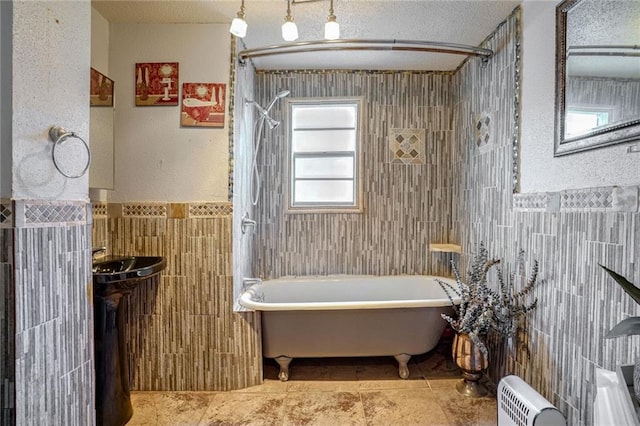 bathroom featuring a bath, tile walls, and a textured ceiling