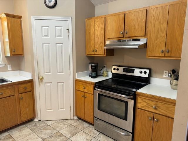 kitchen featuring electric stove, sink, and light tile patterned floors