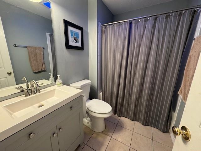 full bathroom with vanity, shower / bath combo, tile patterned floors, and toilet