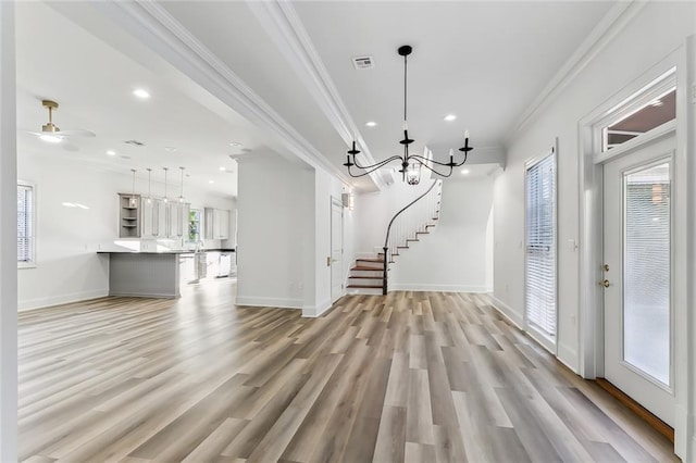 interior space featuring light hardwood / wood-style flooring, ornamental molding, and ceiling fan with notable chandelier