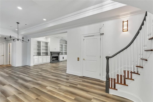 living room with a notable chandelier, wood-type flooring, and ornamental molding