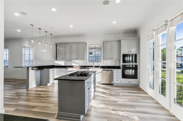 kitchen featuring hanging light fixtures, gray cabinetry, black appliances, a center island, and light wood-type flooring