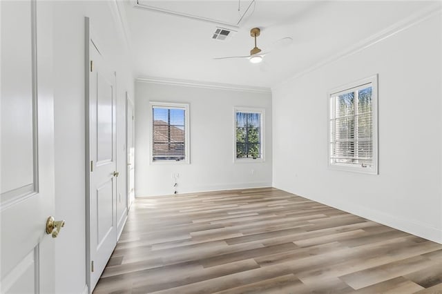 empty room with a healthy amount of sunlight, ornamental molding, and light hardwood / wood-style flooring