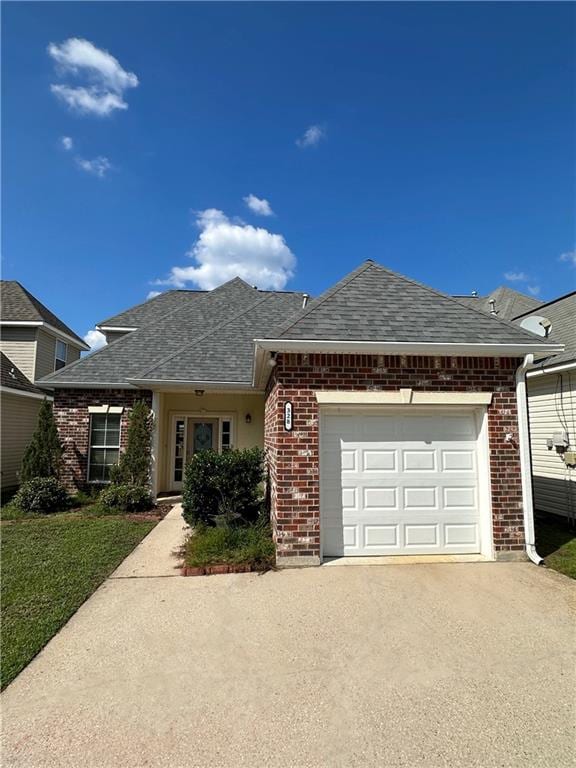 single story home with concrete driveway, an attached garage, and brick siding