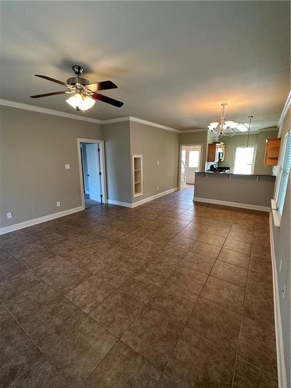 unfurnished living room with dark tile patterned floors, baseboards, ornamental molding, and ceiling fan with notable chandelier