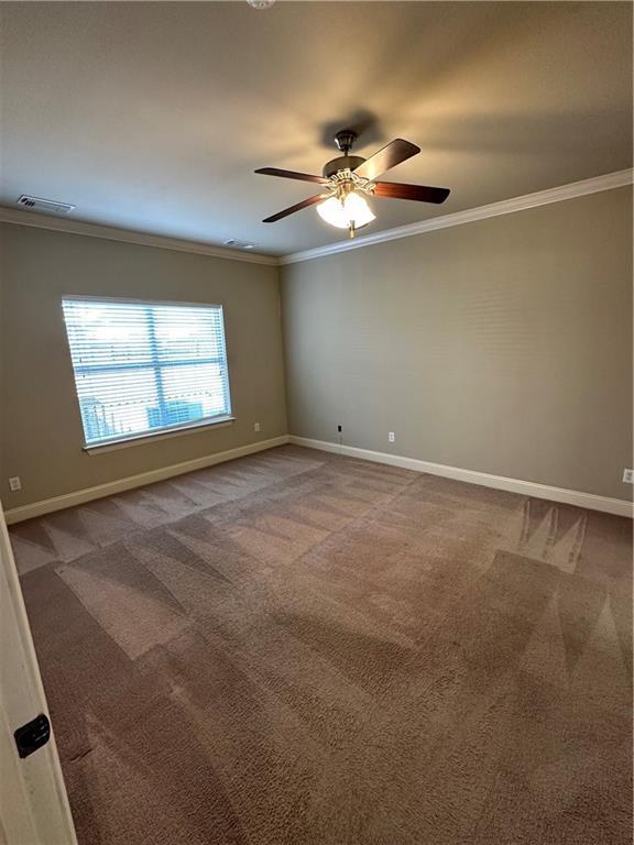 unfurnished room with carpet flooring, visible vents, and ornamental molding