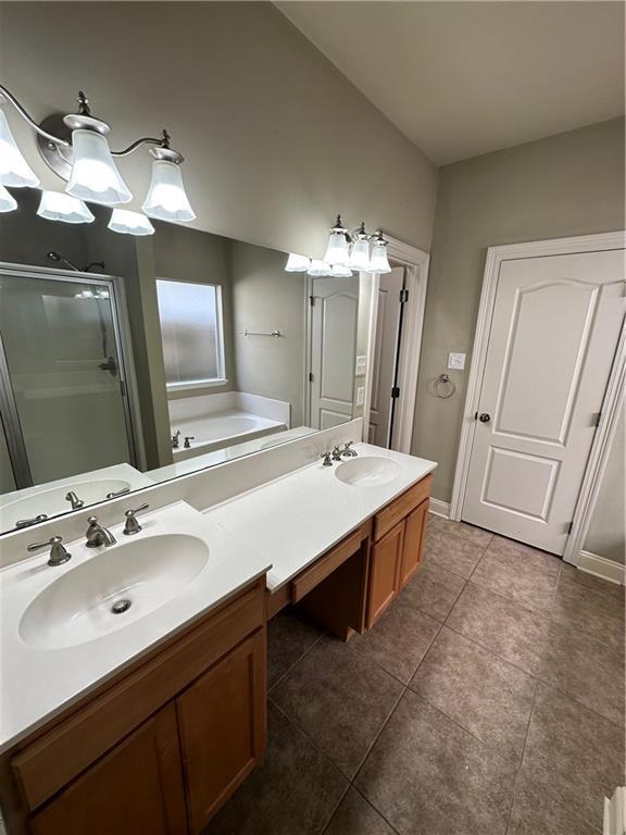 bathroom with a sink, double vanity, a shower stall, and tile patterned flooring