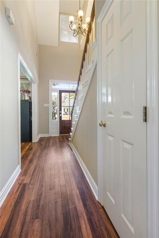 entryway with dark wood-type flooring, a notable chandelier, and a high ceiling