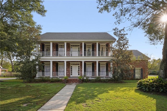 view of front facade with a porch, a front yard, and a balcony