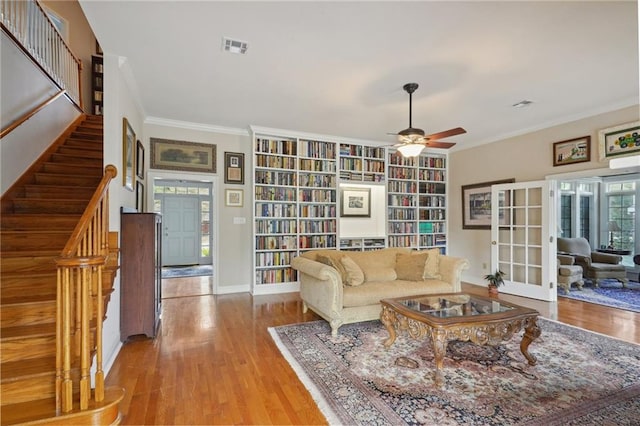 living room featuring light hardwood / wood-style floors, ornamental molding, and ceiling fan