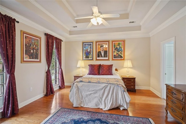 bedroom featuring crown molding, a raised ceiling, light hardwood / wood-style floors, and ceiling fan