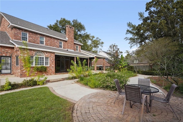 back of property with a patio area and a lawn