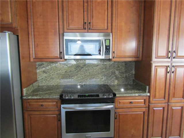 kitchen with dark stone countertops, stainless steel appliances, and backsplash