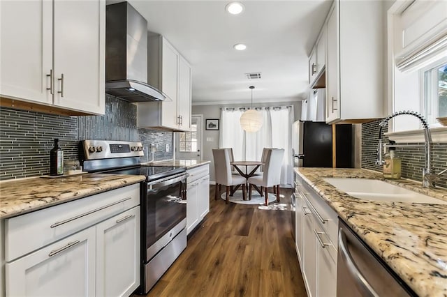 kitchen featuring wall chimney range hood, white cabinets, appliances with stainless steel finishes, dark wood-type flooring, and sink