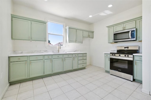 kitchen with sink, light tile patterned floors, appliances with stainless steel finishes, and green cabinets