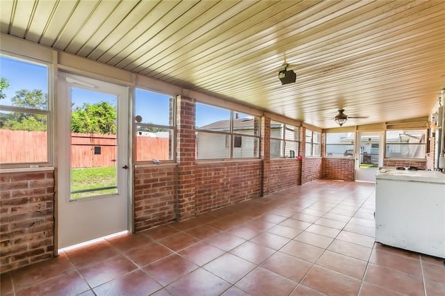 unfurnished sunroom with ceiling fan, wood ceiling, and plenty of natural light