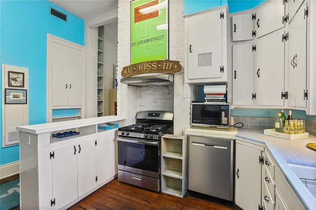 kitchen featuring dark wood-type flooring, white cabinetry, stainless steel appliances, and backsplash