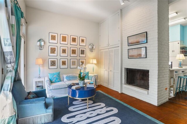 living room featuring dark wood-type flooring and a brick fireplace